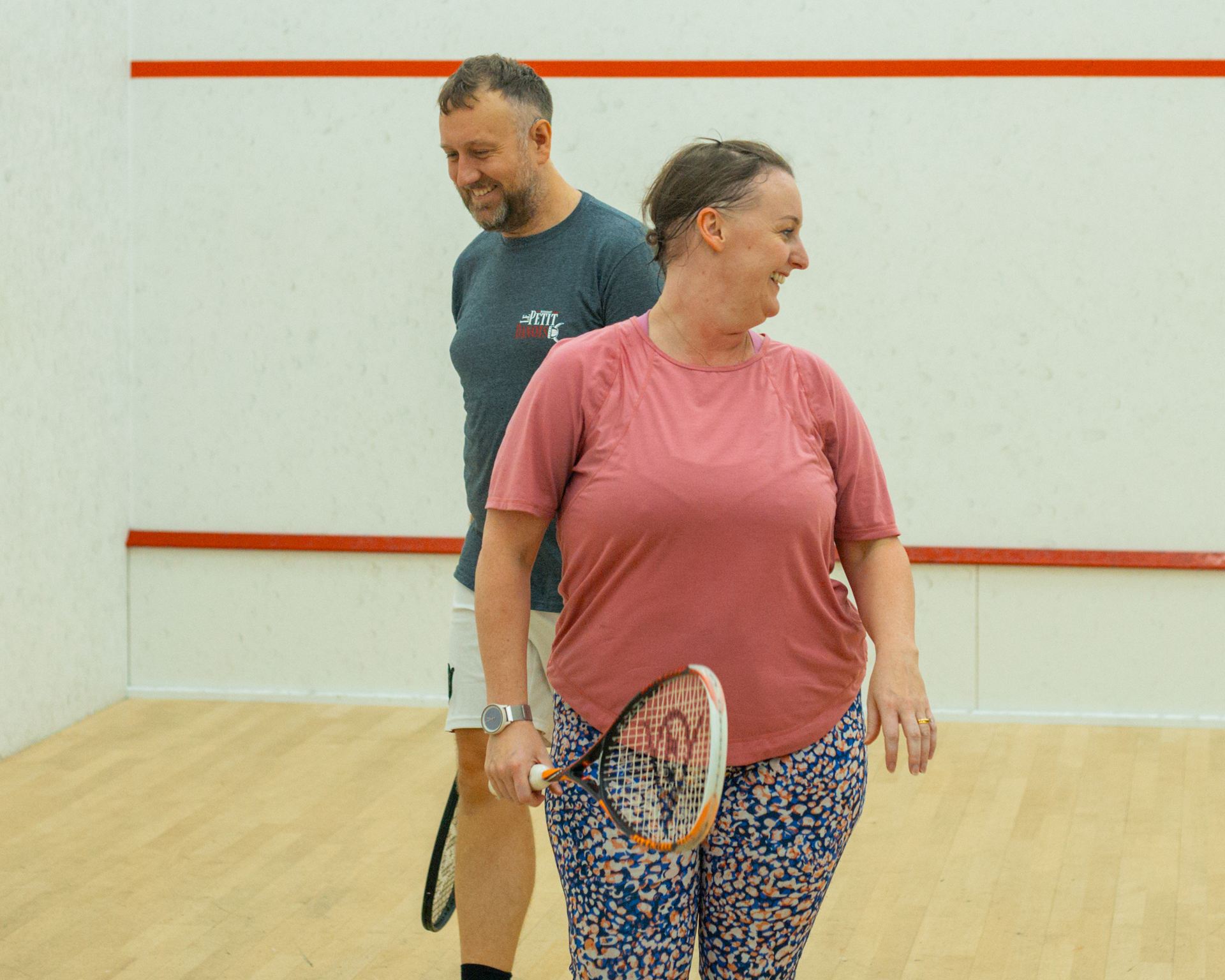 A couple smiling together on a squash court