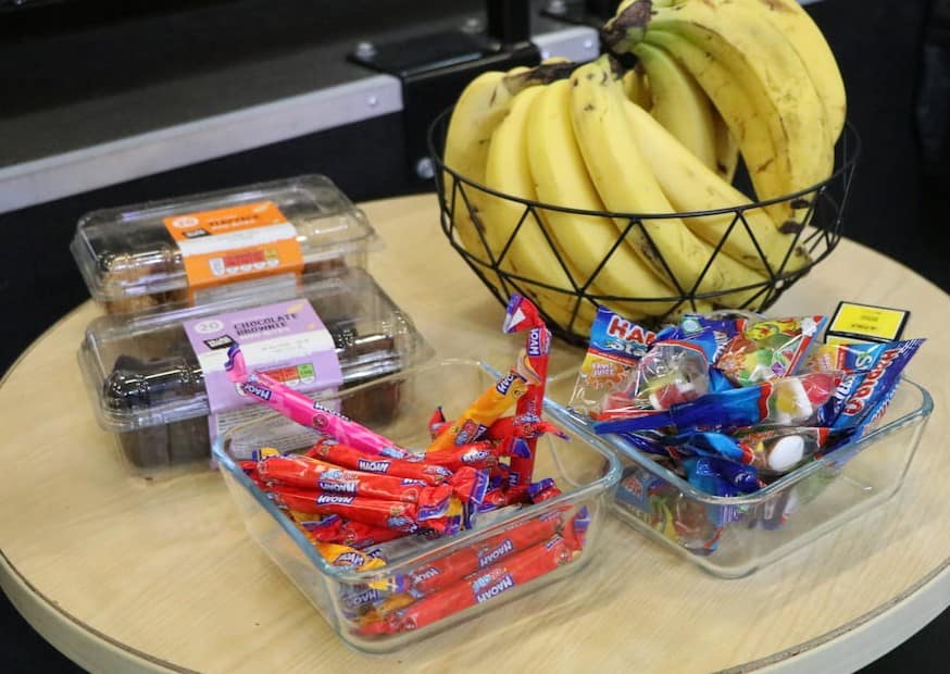 A tournament refuel table with bananas, jellies, cereal bars, and squash snacks