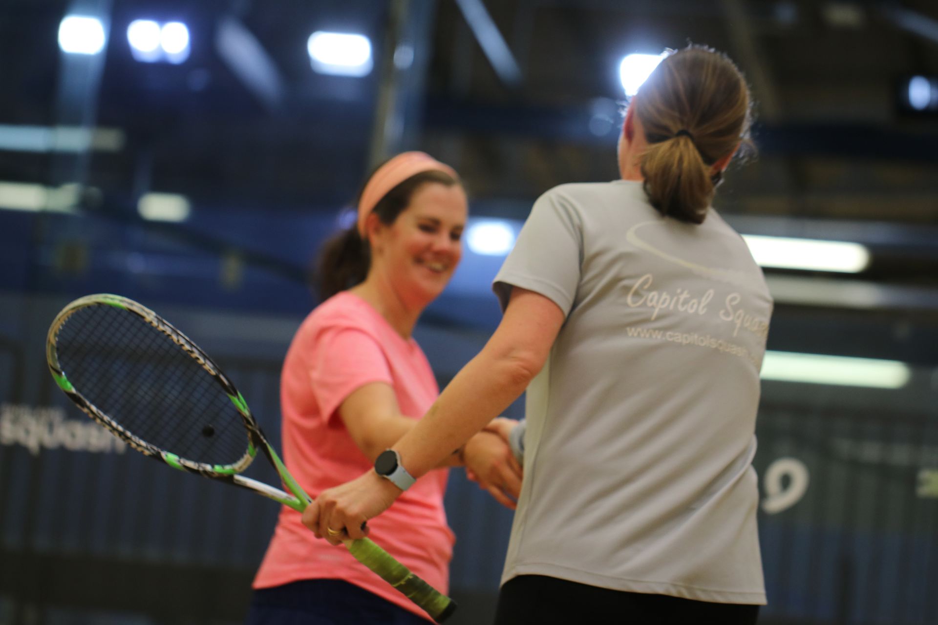 Two women shaking hands after a squash session at a partner venue.