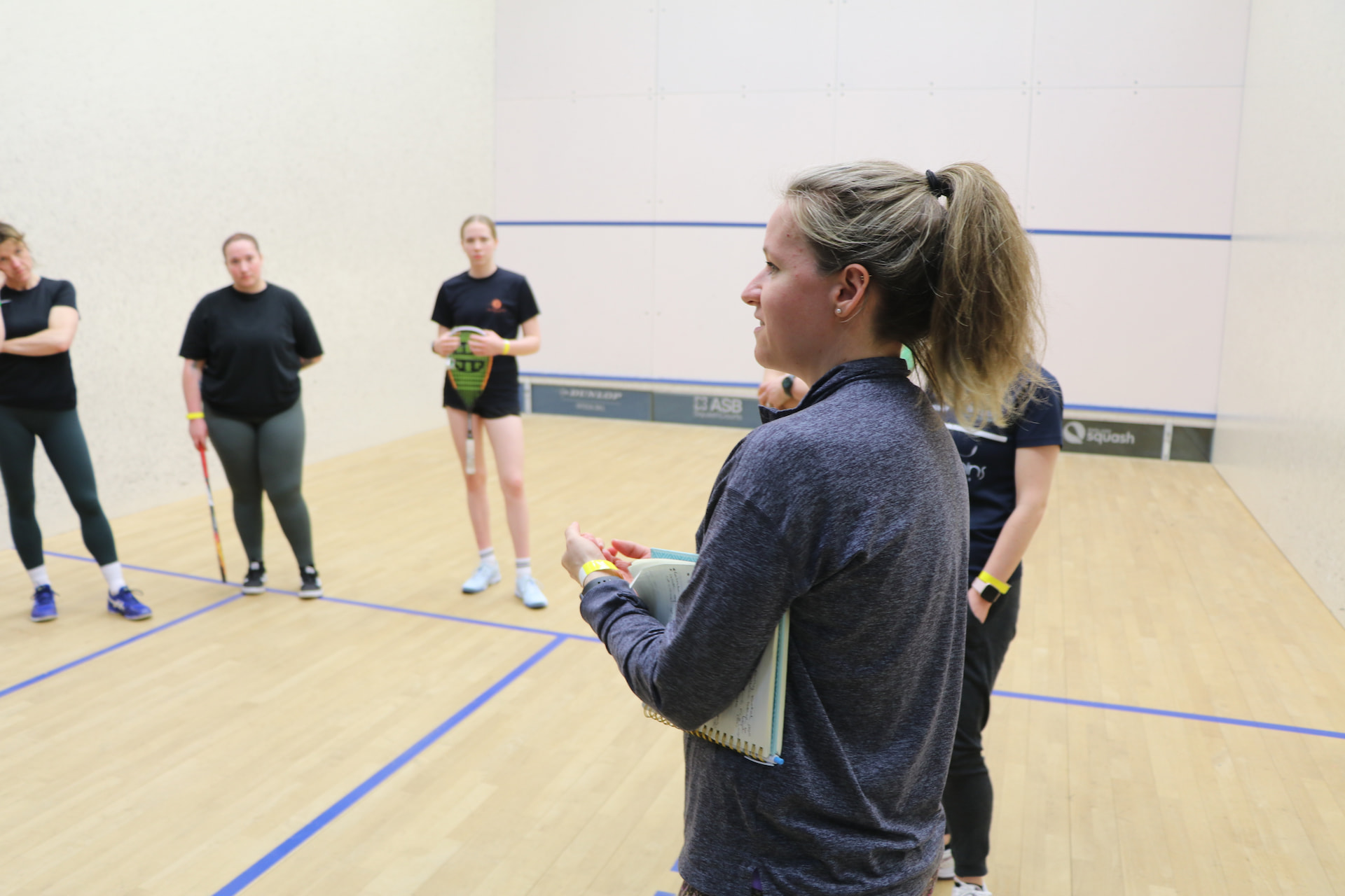 Squash coach leading a group coaching session on court