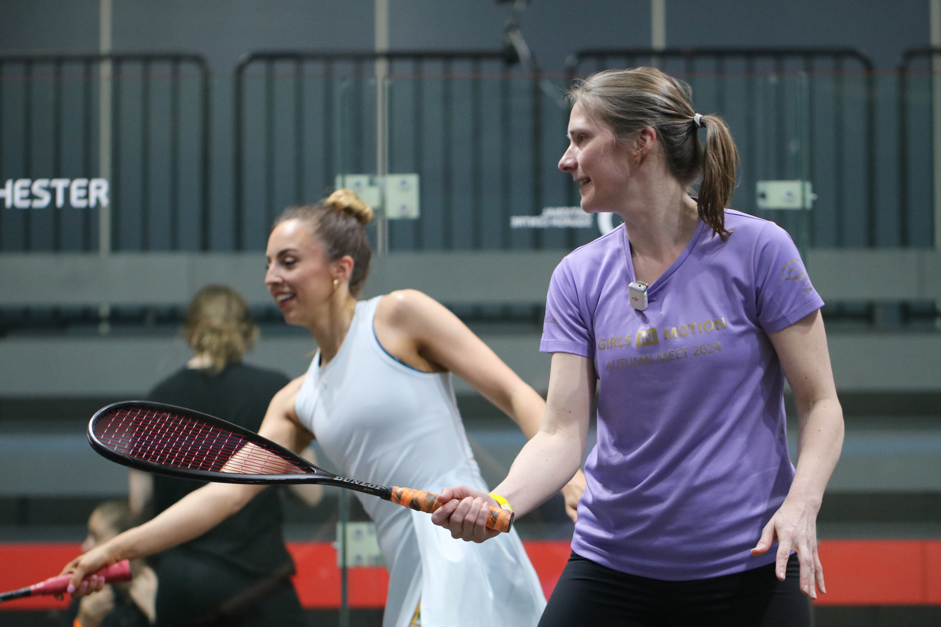 Coach tossing a squash ball to a player during a pro coaching session