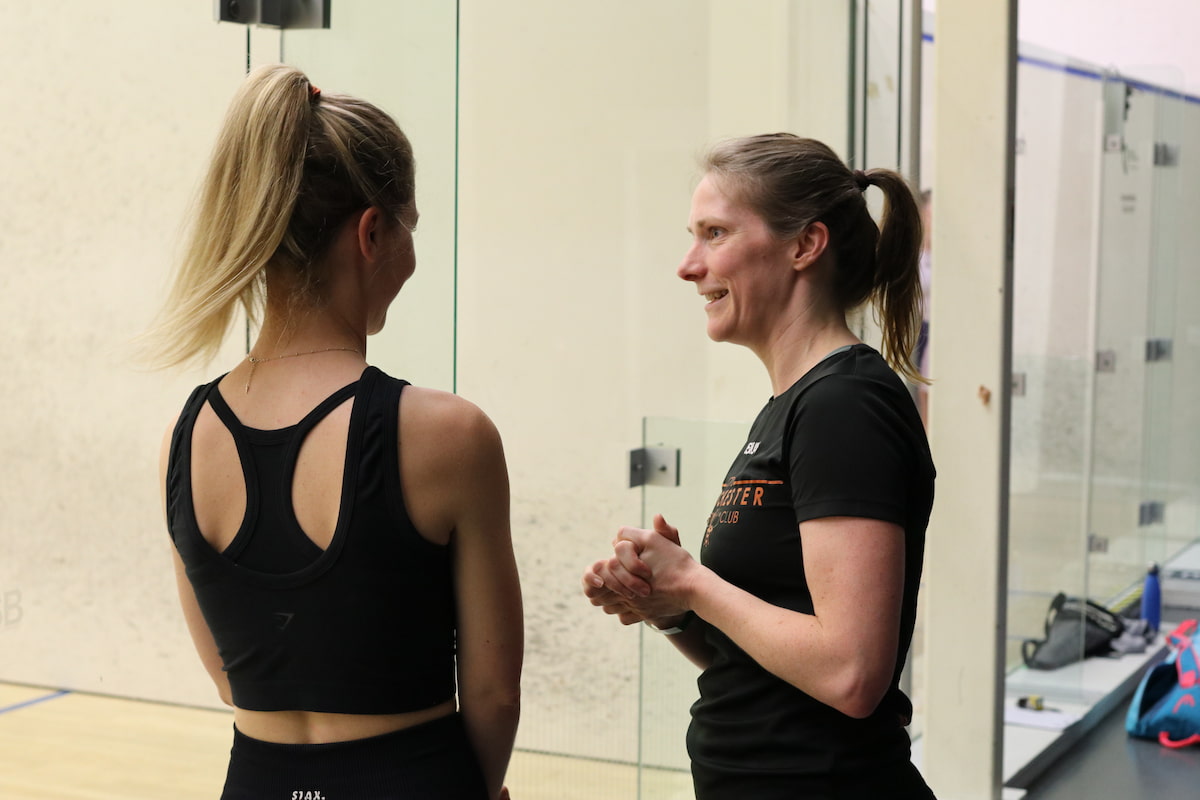 A squash player rallying with their coach during an individual coaching session