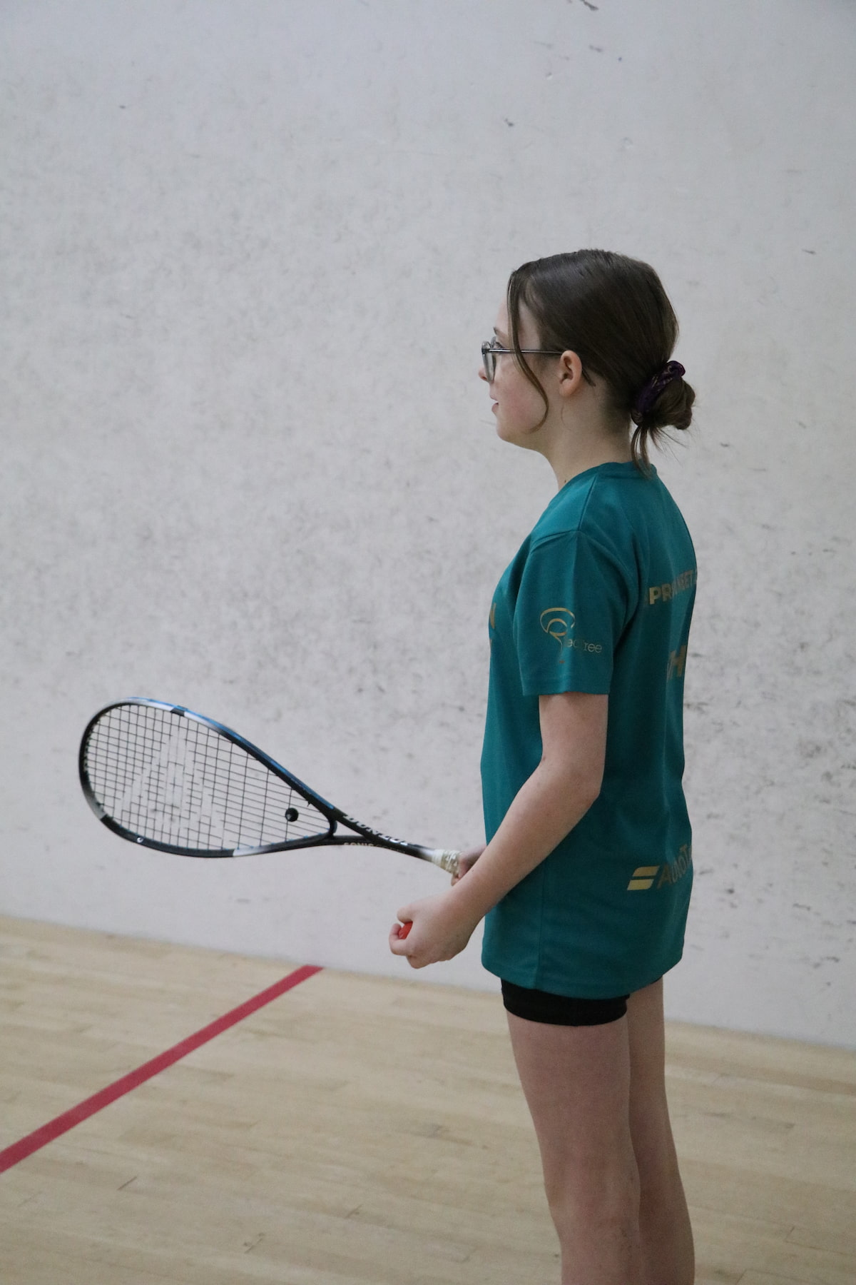 A teenage girl learning squash during a junior coaching session for ages 5-17