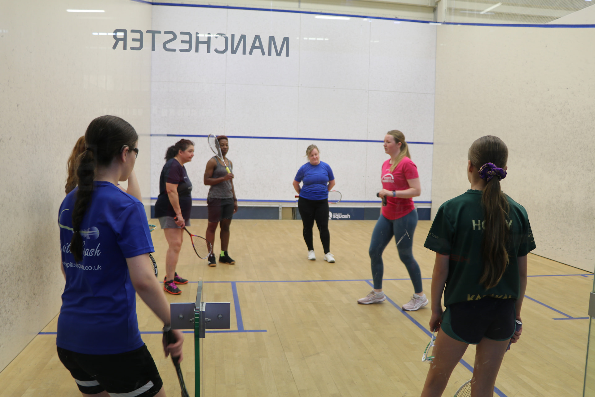 Close-up of squash players' feet and rackets during a coaching session