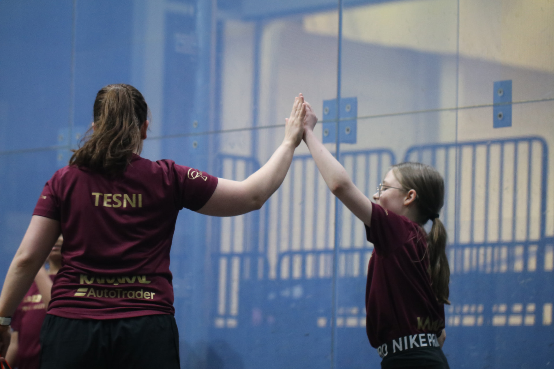 Squash coach and young player high-fiving on court after a session