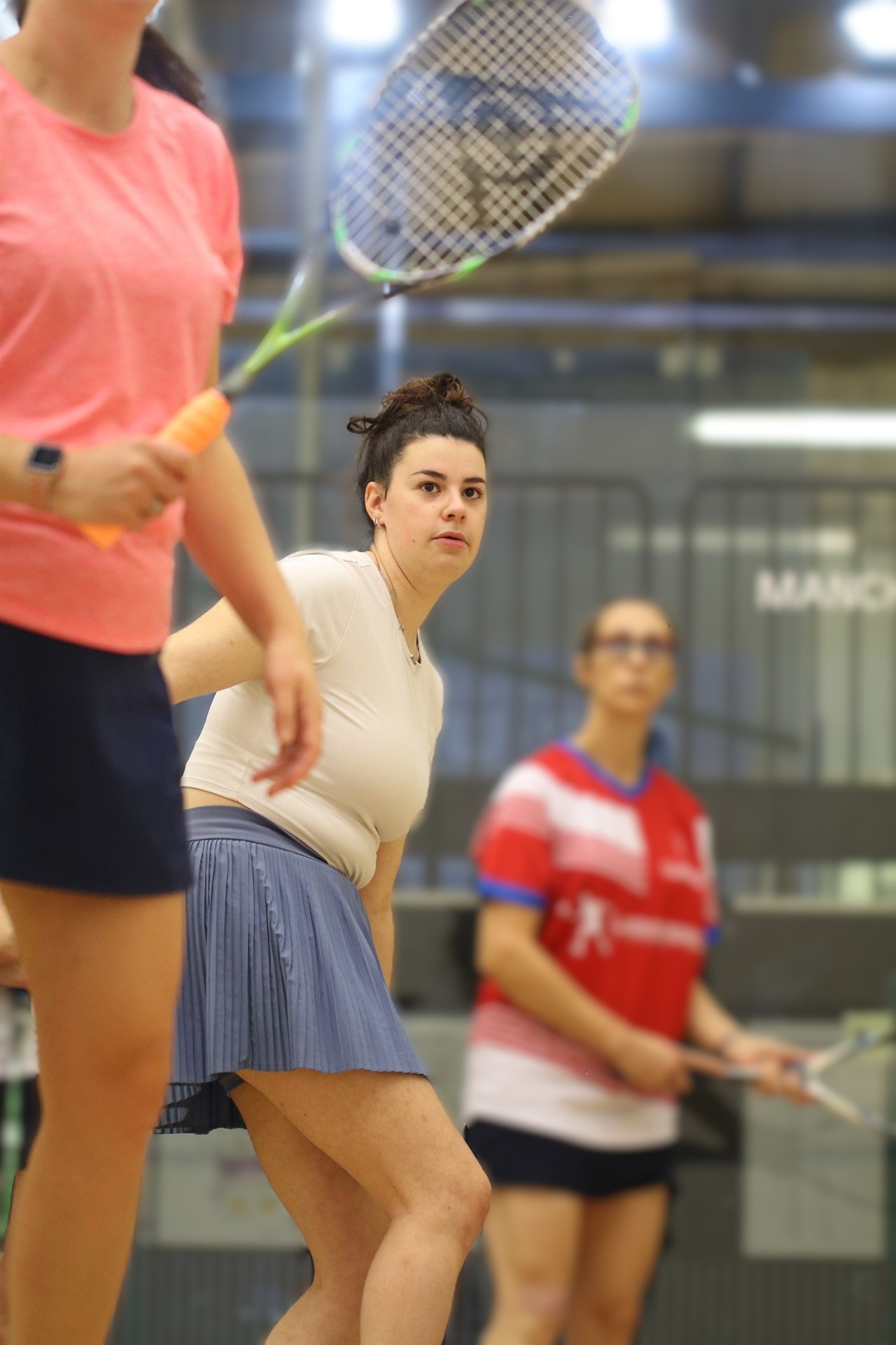 Two women playing squash together during a group coaching session