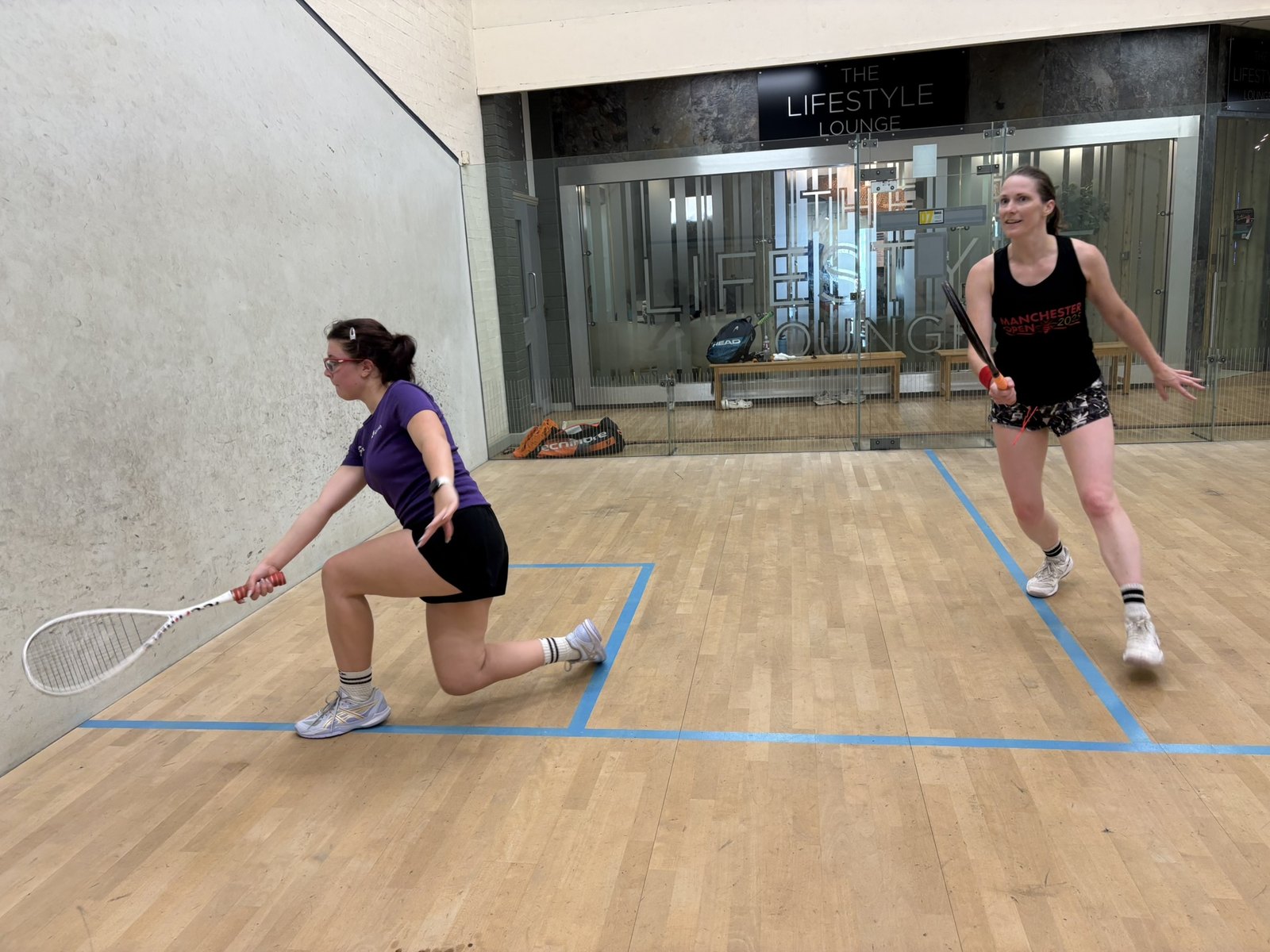 Women playing squash on an indoor court in Manchester